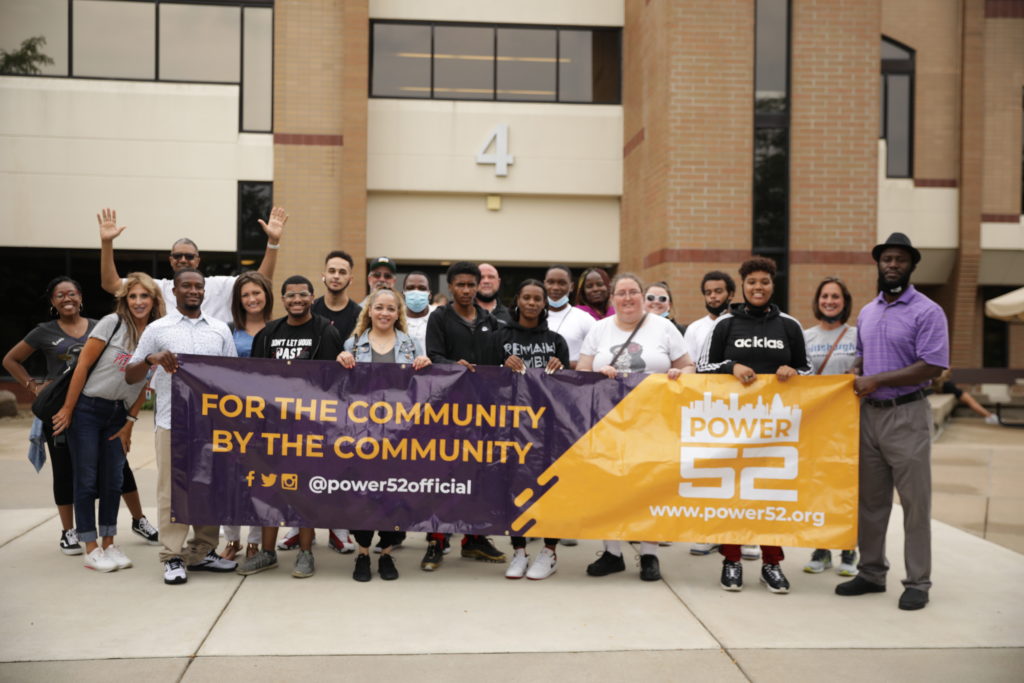 Group photo holding a banner that says for the community by the community