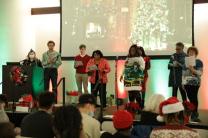 PTC Staff, Faculty, and Students on stage in holiday outfits