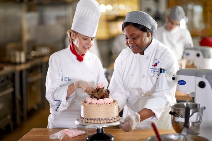 Culinary arts student and teacher decorating a cake.