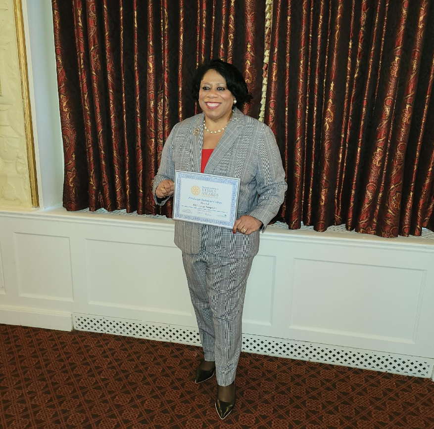Dr. Harvey-Smith posing for a photo as she holds her Excellence in Ethics award.